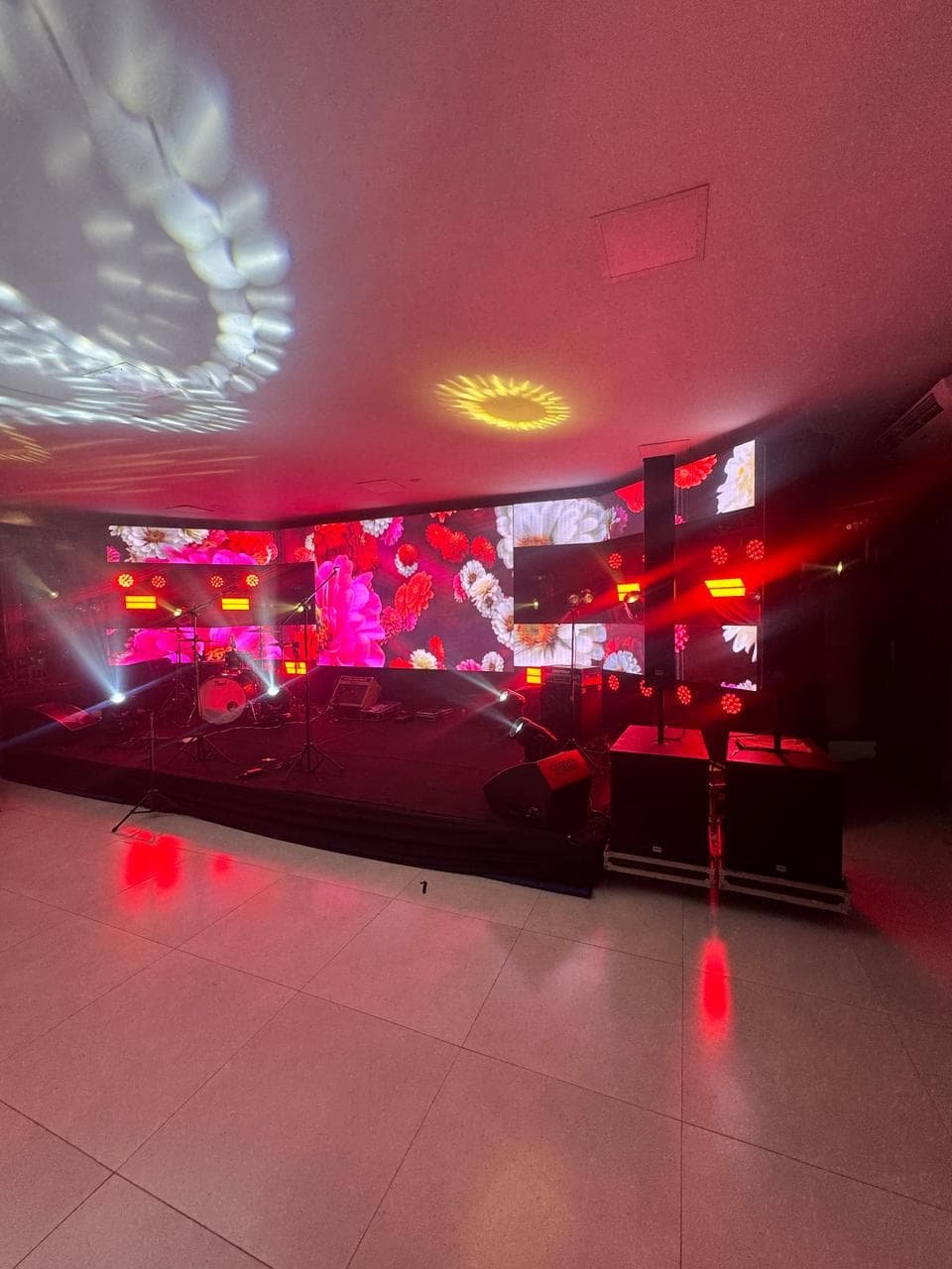 Pista de dança e palco prontos para show, com iluminação profissional vermelha e painéis de LED exibindo visuais dinâmicos.