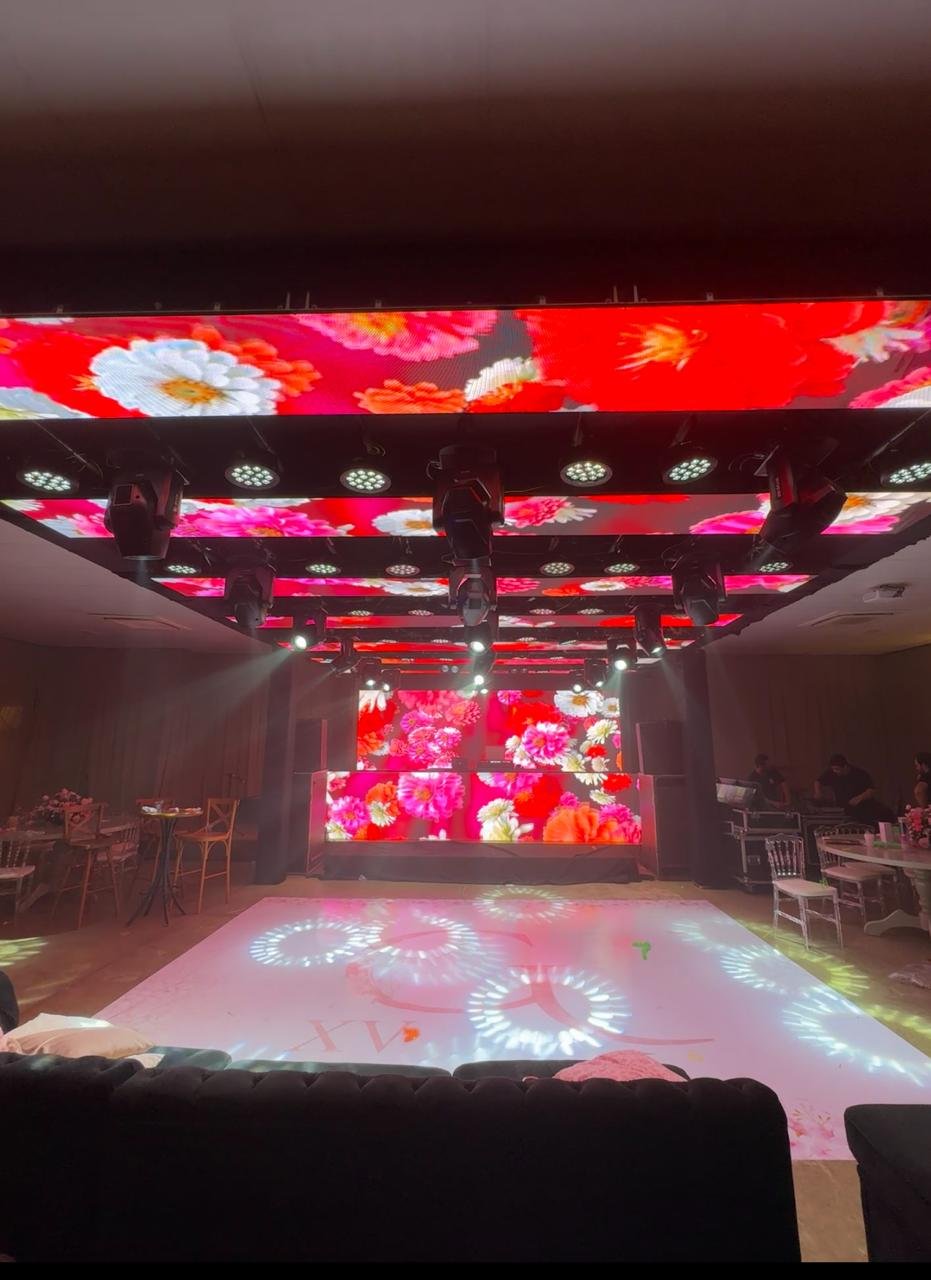 Ambiente de festa imersivo com painéis de LED cobrindo teto e paredes, exibindo projeções florais vermelhas de alta definição.